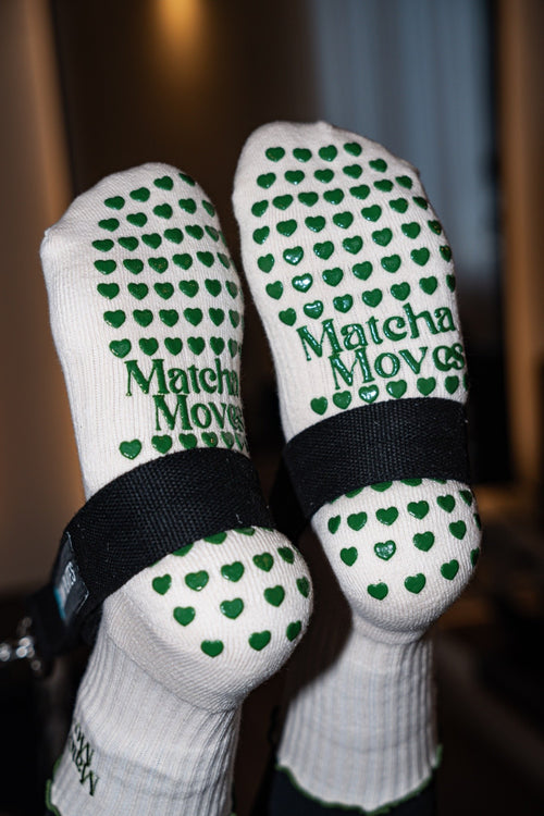 Frau trägt Matcha Moves Pilates Grip Socks beim Reformer Pilates – grüner Herz-Grip Detail