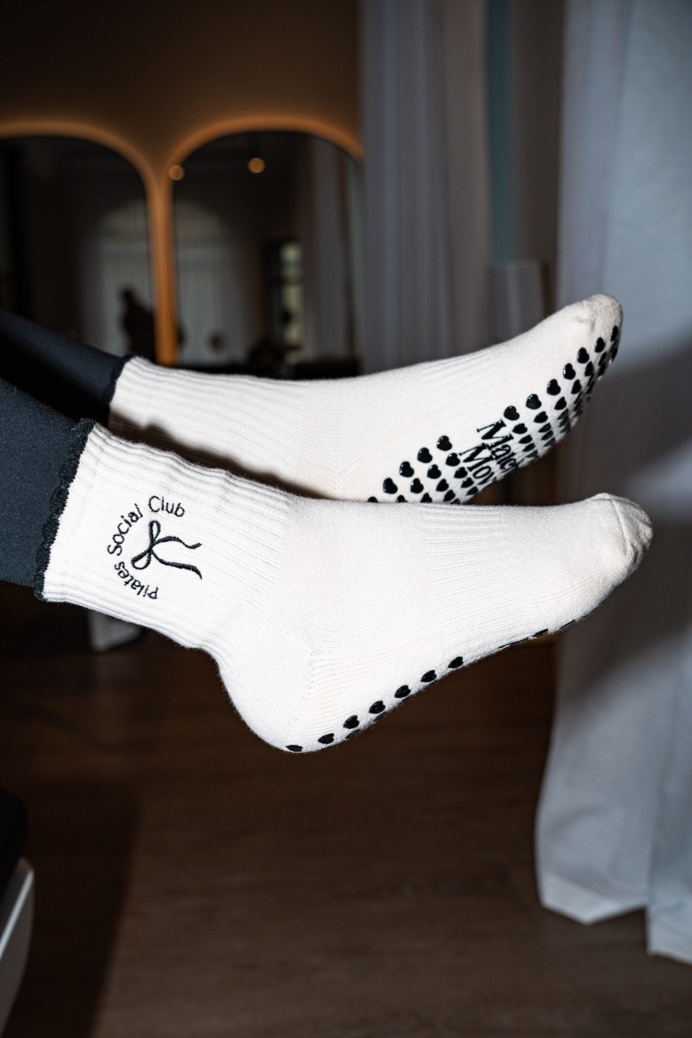 Frau trägt Matcha Moves Pilates Social Club Grip Socks beim Reformer Pilates – schwarzer Herz-Grip Detail